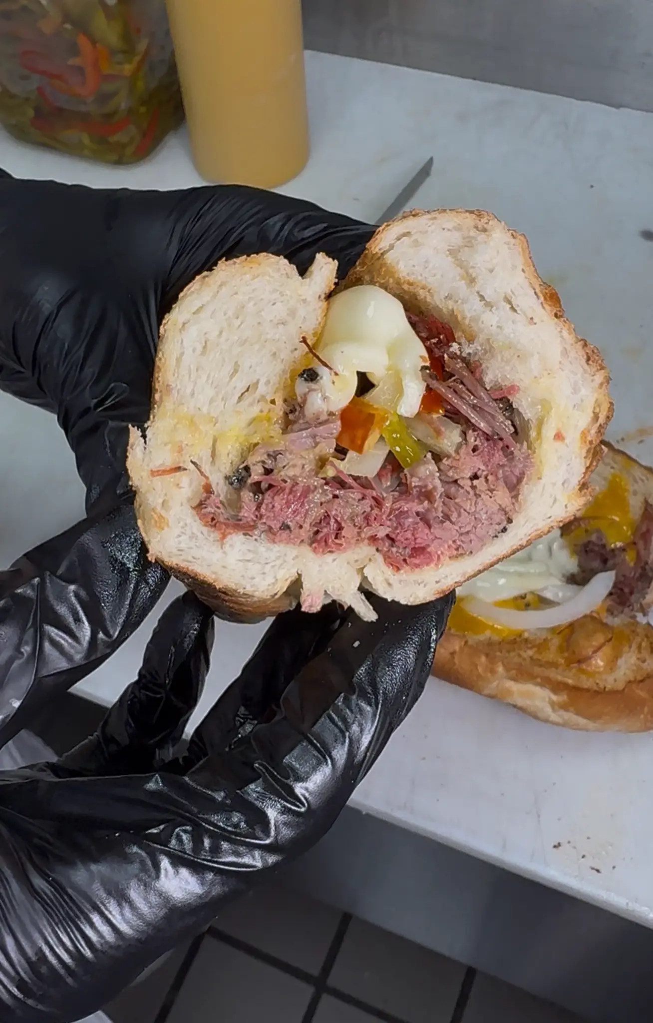 Hoagie House Brisket Sandwich cross section held in black gloves